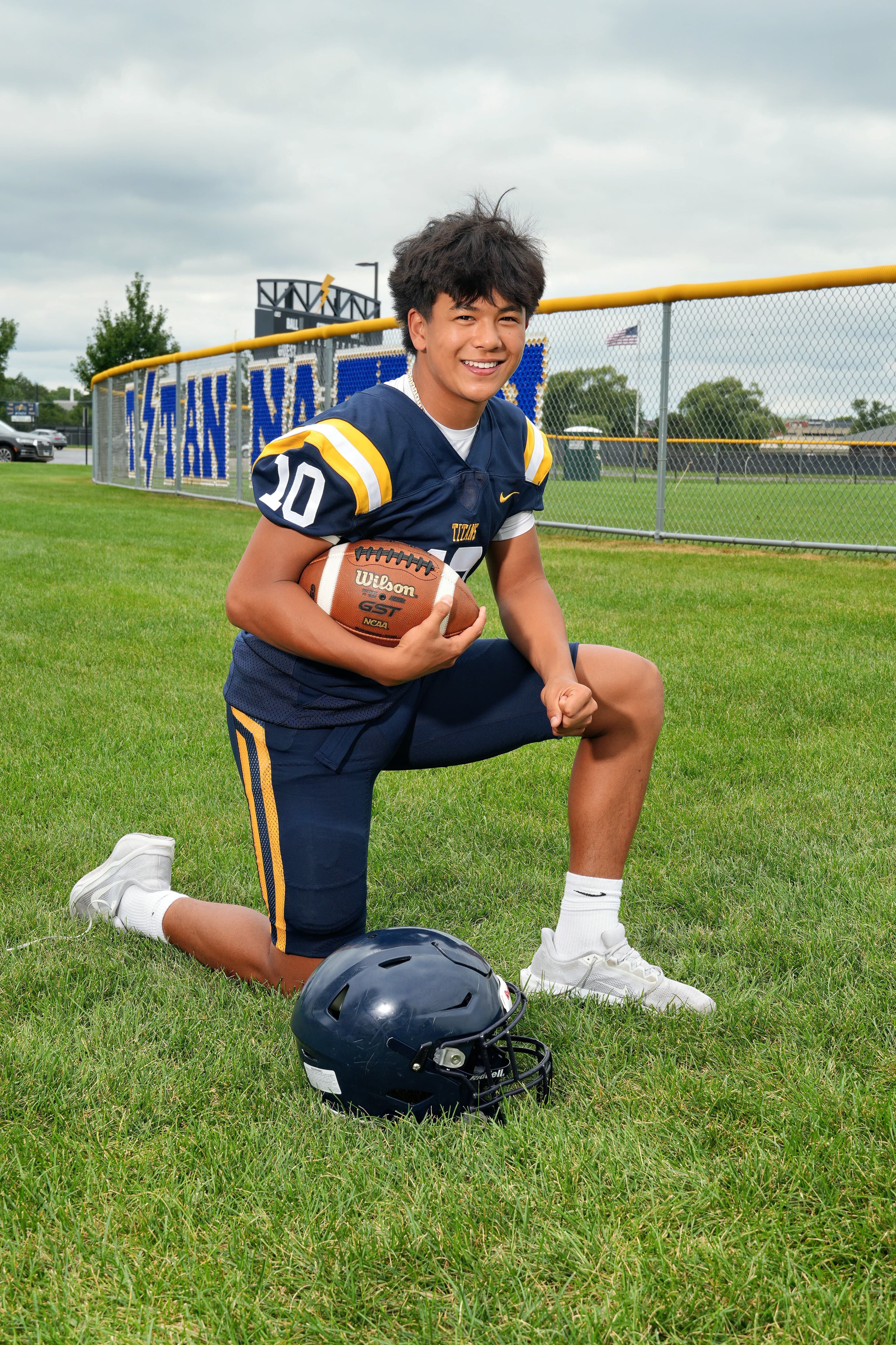 Christopher Diaz, founder of North Shore Spotless, kneeling on the Glenbrook South football field